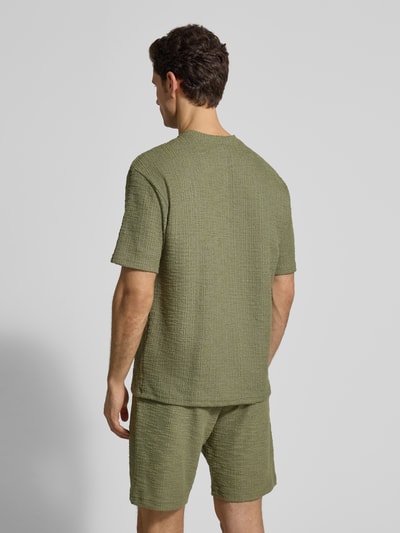 Männermodel trägt T-Shirt mit Strukturmuster und Rundhalsausschnitt von MCNEAL in Grün, Material-Mix, Regular-Fit, Rückenlänge 70 cm, Ganzkörperansicht Rückansicht.