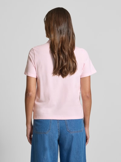 Kobiece modelka ma na sobie Regular Fit Poloshirt aus Baumwoll-Mix od s.Oliver RED LABEL, jednolity kolor różowy, materiał pique, krój regular fit, krótki rękaw, widok całej sylwetki z tyłu.