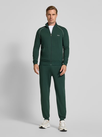 Männermodel trägt Regular Fit Sweatjacke aus Baumwoll-Mix Modell 'Mix&Match' von BOSS in Dunkelgrün mit weißen Akzenten, Ganzkörperansicht von vorne. Herren Sweatjacke von BOSS