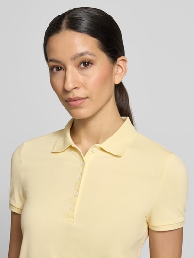 Frauenmodel trägt Slim Fit Poloshirt mit Knopfleiste von Christian Berg Woman aus Baumwoll-Elasthan-Mix, hellgelb, Nahaufnahme Oberkörper.