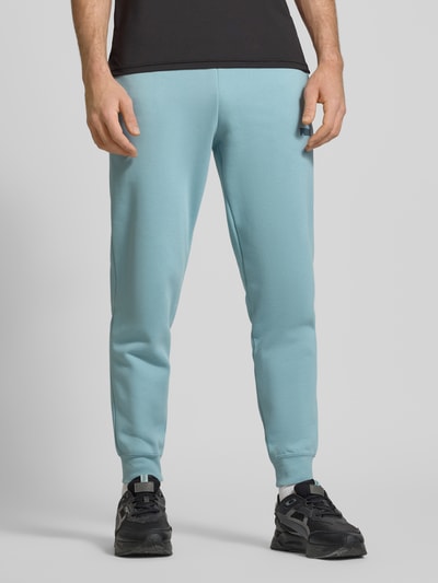 Männermodel trägt Sweatpants mit elastischem Bund von PUMA PERFORMANCE aus Baumwoll-Mix, lockerem Schnitt, Label-Stitching, Eingrifftaschen, Ganzkörperansicht von vorne.