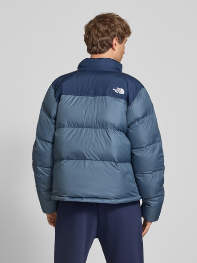 Männermodel trägt Regular Fit Jacke in Stepp-Optik Modell 'SAIKURU' von The North Face in Blau mit Logo-Stitching, Ganzkörperansicht Rückansicht. Rückenlänge bei Größe M: 65 cm, Schulterbreite: 47 cm, Brustweite: 56 cm, Ärmellänge: 67 cm.