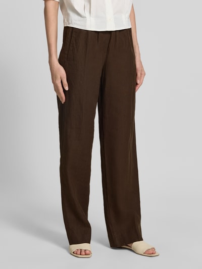 Kobiece modelka nosi Regular Fit Weite Hose aus reinem Leinen Modell 'FARINA' od Brax, jednolity wzór, krój regular fit, czyste len, elastyczny pas z tunelem, kieszenie boczne, detal z logo, ciemnobrązowy kolor, struktura lekko widoczna, widok całej sylwetki z przodu.
