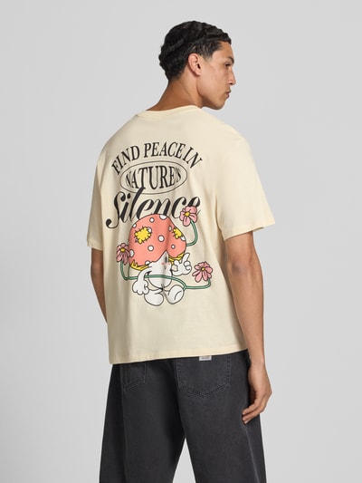 Männermodel trägt T-shirt met motiefprint model 'VINTAGE CARTOON' van Jack & Jones van puur katoen, regular fit, ronde hals, ruglengte maat M 69 cm, vintagelook kleuren en cartoonprint, Ganzkörperansicht Rückansicht.