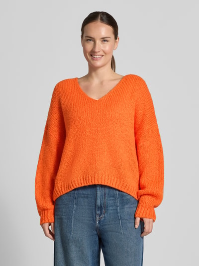 Frauenmodel trägt Oversized Strickpullover mit Mohair-Anteil von Oui in Orange mit gerippten Abschlüssen, Material-Mix, Ganzkörperansicht von vorne.