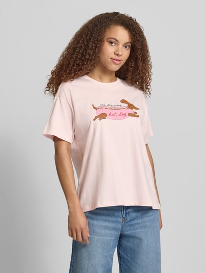 Frauenmodel trägt Regular Fit T-Shirt aus reiner Baumwolle Modell 'VIVVI' von Only, Optik: Unifarben, Motiv-Print, Rundhals, Kurzarm, Materialverarbeitung: Jersey, Material: Baumwolle-Mix, Hellrosa, glatte Textur, Ganzkörperansicht von vorne.