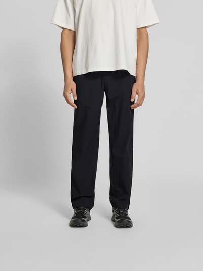 Männermodel trägt Stoffhose mit Stretch-Anteil von Forét in Schwarz, Relaxed-Fit, Elastischer-Material-Mix, Ganzkörperansicht von vorne.
