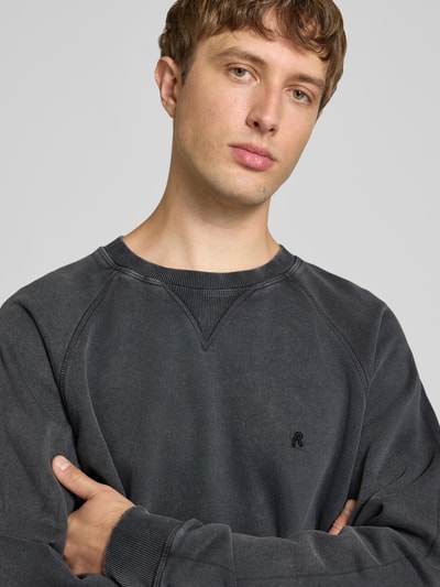Männermodel trägt Regular Fit Sweatshirt aus reiner Baumwolle Modell 'Plush' von Replay in Dunkelgrau, Nahaufnahme Oberkörper. Herren Sweatshirt, Rundhalsausschnitt, elastische Abschlüsse, Rückenlänge 66 cm, Ärmellänge 63 cm.