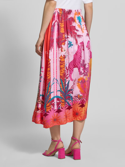 Frauenmodel trägt Midirock aus reiner Viskose mit Allover-Motiv-Print von miss goodlife in kräftigem Pink-Orange, A-Linie, Rückansicht, Ganzkörperansicht. Bundweite Größe S 35 cm, Gesamtlänge S 82 cm, elastischer Bund, Detailreicher Print mit Tiermotiven.