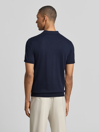 Männermodel trägt Regular Fit Poloshirt aus reiner Baumwolle Modell 'BERG' von SELECTED HOMME in Unifarben, Feinripp, Ganzkörperansicht Rückansicht.
