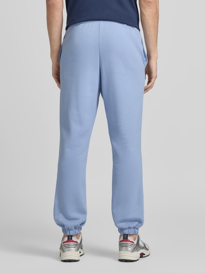 Męski model nosi Regular Fit Sweatpants aus Baumwoll-Mix od Lacoste, jasnoniebieski, krój regular fit, elastyczne mankiety, dzianina dresowa, logo, widok całej sylwetki z tyłu.