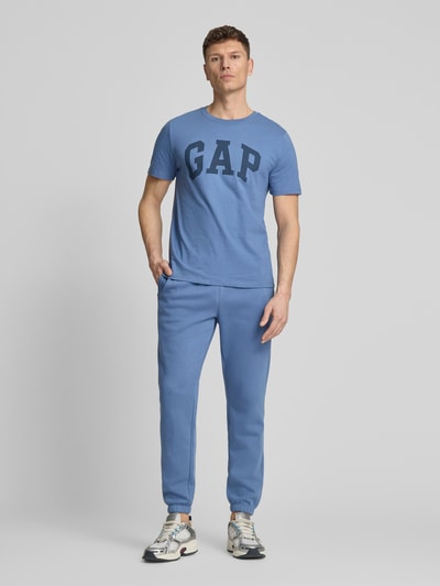 Männermodel trägt T-Shirt mit Logo und Rundhalsausschnitt von GAP, Reine Baumwolle, Regular-Fit, Rückenlänge 72 cm, Ganzkörperansicht von vorne.