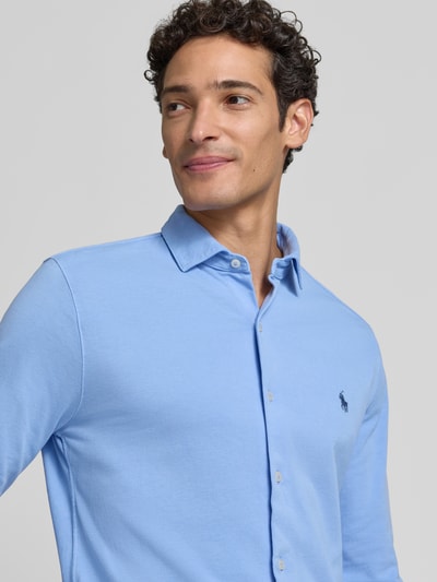 Männermodel trägt Slim Fit Freizeithemd aus reiner Baumwolle von Polo Ralph Lauren in Hellblau, glatte Textur, Nahaufnahme Oberkörper