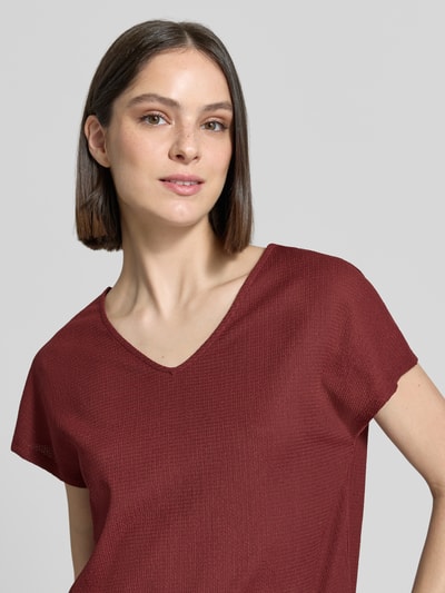 Frauenmodel trägt Relaxed Fit T-Shirt mit Allover-Muster von s.Oliver RED LABEL in Bordeaux, Jersey, V-Ausschnitt, Optik:Allover-Muster, Passform: Relaxed-Fit, Materialverarbeitung: Jersey, Nahaufnahme Oberkörper.