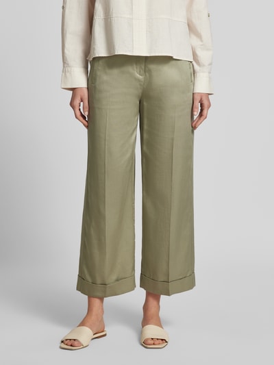 Kobiece model prezentuje oliwkowo-zielone Wide Leg Pants mit Bindegürtel Modell 'Meeri bloom' od OPUS z lyocellu i bawełny, szerokie nogawki, francuskie kieszenie, ozdobny pasek, guzik i zamek z przodu, imitowane tylne kieszenie, wywinięty dół nogawek, szerokość w rozmiarze 36: 40 cm, długość nogawki od wewnątrz: 68 cm, widok na całe ciało od przodu.