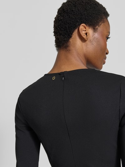 Vrouwenmodel draagt knielang jurk met stretch, getailleerde pasvorm, ronde hals, met cut-outs en siersteentjes, Model 'CLAUDIE' van GUESS, elastische materiaalmix, detailopname rugaanzicht.