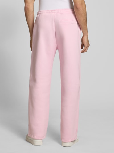 Männermodel trägt Sweatpants mit elastischem Bund von REVIEW in Rosa, Relaxed-Fit, Gesäßtasche, Material-Mix, Ganzkörperansicht Rückansicht.