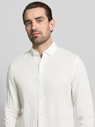 Męski model nosi Regular Fit Leinenhemd mit Button-Down-Kragen von Scotch & Soda z lnu, listwa guzikowa, kołnierzyk typu button down, długość tyłu w rozmiarze M 76 cm, szerokość w rozmiarze M 44 cm, długość rękawów w rozmiarze M 64 cm, tekstura gładka, kolor biały, Nahaufnahme górnej części ciała.