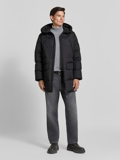 Männermodel trägt Regular Fit Daunenjacke mit Kapuze von Marc O'Polo, unifarben, wasserabweisend, Pattentaschen, Ganzkörperansicht von vorne.