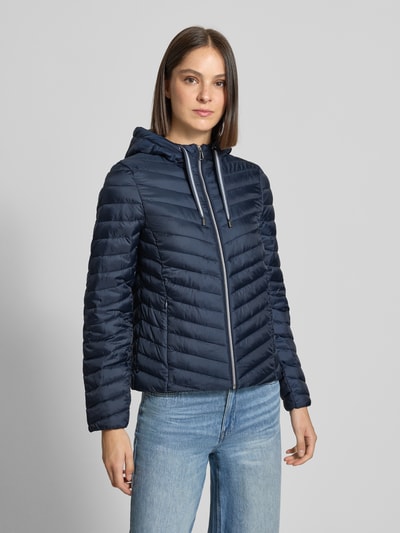 Frauenmodel trägt dunkelblaue Regular Fit Steppjacke mit Kapuzenkragen von Tom Tailor, glatte Struktur, Damen Steppjacke, Ganzkörperansicht von vorne.