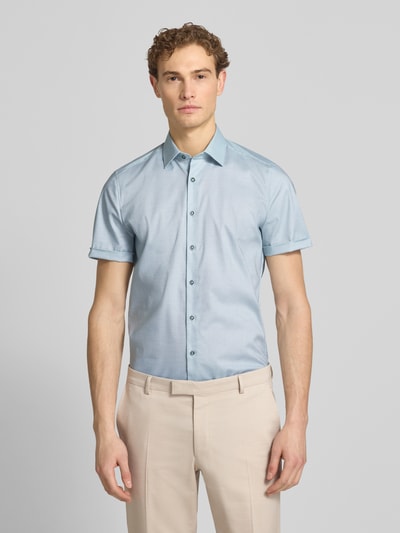 Männermodel trägt Slim Fit Business-Hemd mit Kentkragen von OLYMP Level Five in Hellblau aus Baumwoll-Elasthan-Mix, Ganzkörperansicht von vorne.