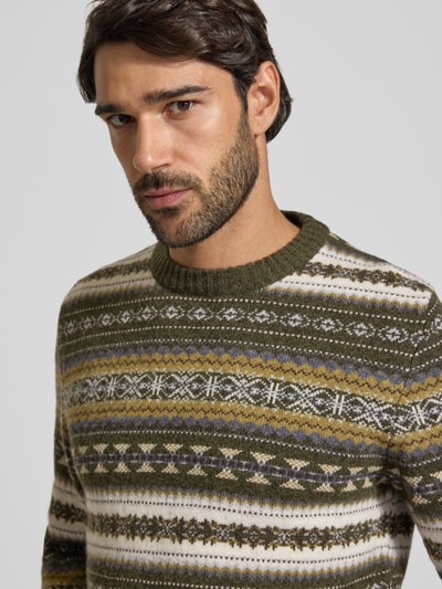 Männermodel trägt Slim Fit Strickpullover aus Baumwoll-Mix mit Rundhalsausschnitt von MCNEAL, gemustert in Grün und Beige, Nahaufnahme Oberkörper. Baumwoll-Mix, gerippte Blende und Abschlüsse, langärmliges Design