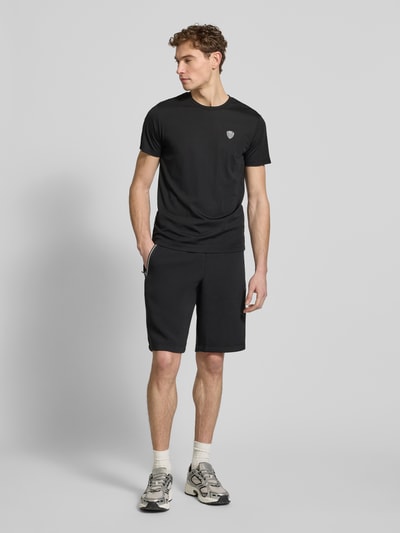 Männermodel trägt Shorts mit elastischem Bund von EA7 Emporio Armani in Schwarz, Material-Mix mit Viskose, Regular Fit, Ganzkörperansicht von vorne.