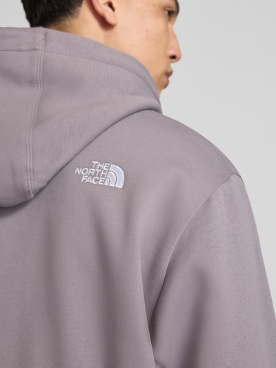 Männermodel trägt Regular Fit Hoodie mit Logo-Print von The North Face aus Baumwoll-Mix, hellgraue Farbe, Detailaufnahme Schulterperspektive.