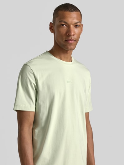 Männermodel trägt Regular Fit T-Shirt aus Baumwoll-Mix Modell 'TCHUP' von BOSS Orange in Hellgrün, glatte Textur, Nahaufnahme Oberkörper.
