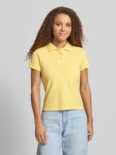 Frauenmodel trägt kurzärmliges Poloshirt in Piquéoptik mit Kragen und Logostickerei von REVIEW, Reine Baumwolle, Slim Fit, hellgelb, Ganzkörperansicht von vorne.