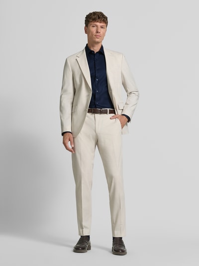 Männermodel trägt dunkelblaues Slim Fit Businesshemd aus reiner Baumwolle Modell 'H-HANK-K' von BOSS zu cremefarbenem Anzug, Ganzkörperansicht von vorne.