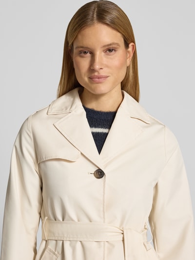 Vrouwenmodel draagt Regular Fit Trenchcoat aus Baumwoll-Mix van s.Oliver RED LABEL in effen kleuren met reverskraag, labelapplicatie, enkelvoudige knoopsluiting, tailleriem, rugpas, gun flap, schoudertrensjes, lange mouw met trensje, waterafstotend, binnenzak, zij-steekzakken, twill, katoenmix. Nahaufnahme bovenlichaam.