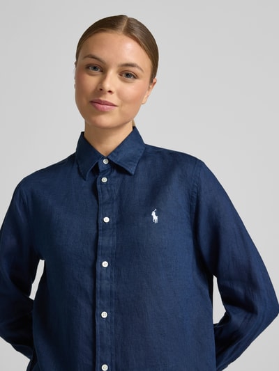 Kobiece model nosi Bluzka koszulowa z czystego lnu od Polo Ralph Lauren, luźny krój, kołnierzyk koszulowy, listwa guzikowa, wyhaftowane logo, długość tyłu 70 cm, długość rękawów 58 cm, kolor granatowy, faktura lnu, widok na górną część ciała z przodu.