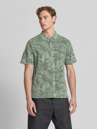 Męski model nosi Regular Fit Poloshirt mit floralem Allover-Print Modell 'Hawaii' von JACK & JONES premium z bawełny, krótki rękaw, długość tyłu 68 cm, widok z przodu całej sylwetki.