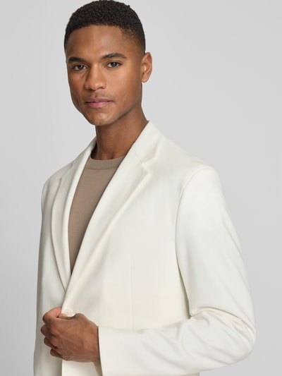 Męski model trägt Regular Fit Blazer mit Reverskragen Modell 'Catory' von Drykorn, mieszanka bawełny, kieszenie z wypustkami, listwa z 2 guzikami, kolor kremowy, detaliczna faktura materiału, Nahaufnahme Oberkörper. Długość tyłu w rozmiarze 50: 70 cm, szerokość ramion w rozmiarze 50: 44 cm, długość rękawów w rozmiarze 50: 64 cm.