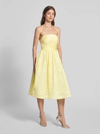 Frauenmodel trägt Minikleid mit floralem Allover-Stitching von Hey Kyla in zartem Gelb, schulterfrei, tailliert, ausgestellter Rock, Ganzkörperansicht von vorne.