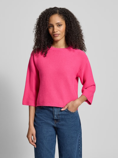 Modelka kobieca nosi Oversized Strickpullover aus Viskose-Mix mit Stehkragen od More & More, mieszanka wiskozy, krój oversized, stójka, opuszczone ramiona, długość tyłu w rozmiarze 36: 51 cm, długość rękawów: 41 cm, intensywny różowy kolor, gładka dzianina, widoczne tekstury, widok całej sylwetki z przodu.