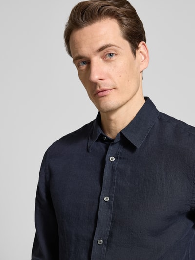 Mężczyzna nosi Regular Fit Leinenhemd mit Kentkragen Modell 'Spenser' od Tiger Of Sweden, kolor ciemnogranatowy, len, krój regular fit, detaliczne ujęcie górnej części ciała, Szerokość w rozmiarze 40: 48 cm, długość pleców 77 cm, długość rękawa 69 cm.