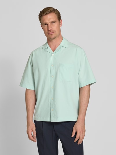 Männermodel trägt Relaxed Fit Freizeithemd mit Seersucker-Verarbeitung Modell 'LAPISY_M' von BOSS Orange in Mintgrün, unifarben, mit Resortkragen, Brusttasche und kurzarm, ganzkörperansicht von vorne.