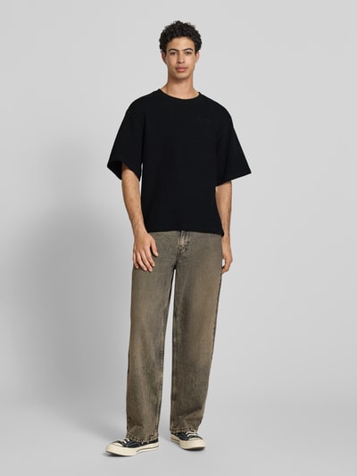 Männermodel trägt Relaxed Fit T-Shirt mit Strukturmuster von KARL KANI aus Reine Baumwolle, Logo-Stitching, Rundhalsausschnitt, Herren T-Shirt, Ganzkörperansicht von vorne.