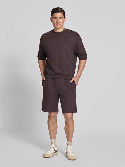 Männermodel trägt Relaxed Fit Sweatshorts aus reiner Baumwolle von Lacoste, Optik: Unifarben, Logo-Detail, Ganzkörperansicht von vorne.