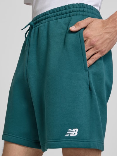 Mężczyzna nosi Relaxed Fit Shorts mit Logo-Stitching von New Balance z mieszanki bawełny, wyhaftowane logo, tunel, szerokość w rozmiarze M: 42 cm, długość wewnętrzna nogawki: 18 cm, detaliczny widok na uda i pas, z przodu