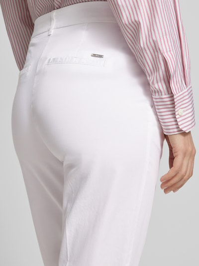 Frauenmodel trägt Hose in verkürzter Passform Modell 'MARON' von Brax aus weißem Baumwoll-Mix mit Lyocell, Detailaufnahme Rückansicht.