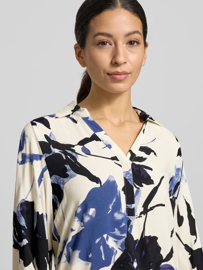 Vrouwenmodel draagt Blusenshirt met V-hals model 'BENE' van Soyaconcept van zuivere viscose, losse pasvorm, blauwe en zwarte bloemenprint, detailopname bovenlichaam.