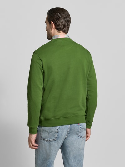Mannenmodel draagt groen sweatshirt met ronde hals van Scotch & Soda, puur katoen, regular fit, labelstitching, ruglengte maat M 67 cm, mouwlengte 64 cm. Ganzkörperansicht Rückansicht.