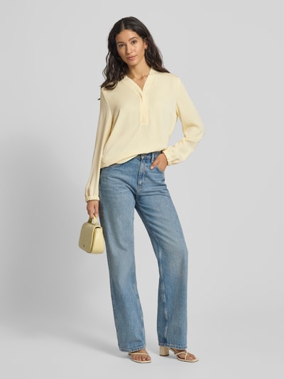 Vrouwenmodel draagt Regular fit blouse met V-hals van Marc Cain, labeldetail, lichte stof, zachte gele kleur, ruglengte 64 cm, mouwlengte 61 cm, geheelvooraanzicht.