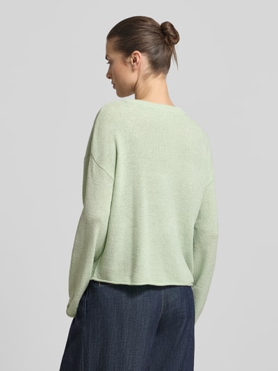 Vrouwenmodel draagt Relaxed Fit Strickpullover mit U-Boot-Ausschnitt van Tom Tailor Denim in effen lichtgroen fijngebreid materiaal, lange mouw, rolzoom aan mouw en zoom, achteraanzicht volledige lichaamsopname.