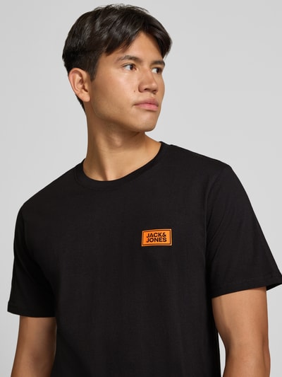 Männermodel trägt Regular Fit T-Shirt aus reiner Baumwolle mit Label-Detail von JACK & JONES in Schwarz, Nahaufnahme Oberkörper.