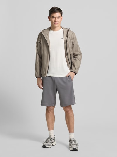Männermodel trägt Jacke mit Zweiwege-Reißverschluss von Armani in Beige, Regular-Fit mit Kapuze, Reißverschlusstaschen, Ganzkörperansicht von vorne. Rückenlänge 67 cm, Schulterbreite 54 cm, Brustweite 60 cm, Ärmellänge 63 cm bei Größe 50.
