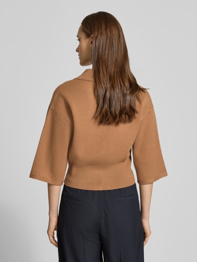 Frauenmodel trägt Strickjacke aus Viskose-Mix Modell 'SHYLA' von Noisy May in Camel mit gerippten Abschlüssen, lockerer Passform, Ganzkörperansicht Rückansicht.